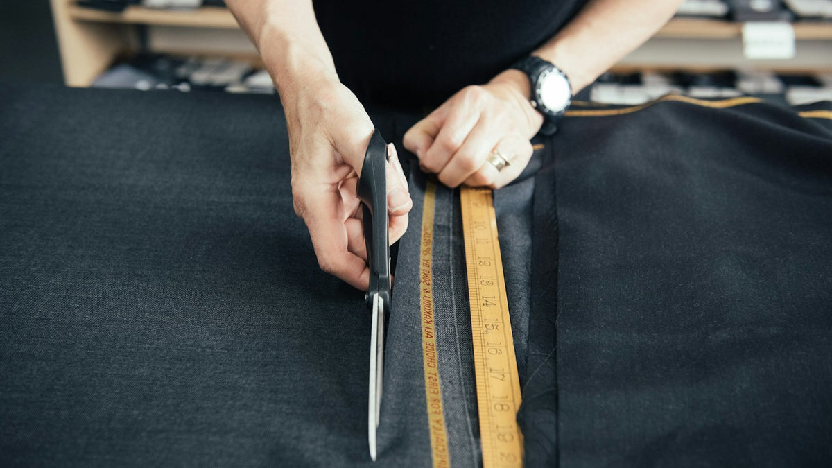 Tailor cutting a length of fabric with scissors